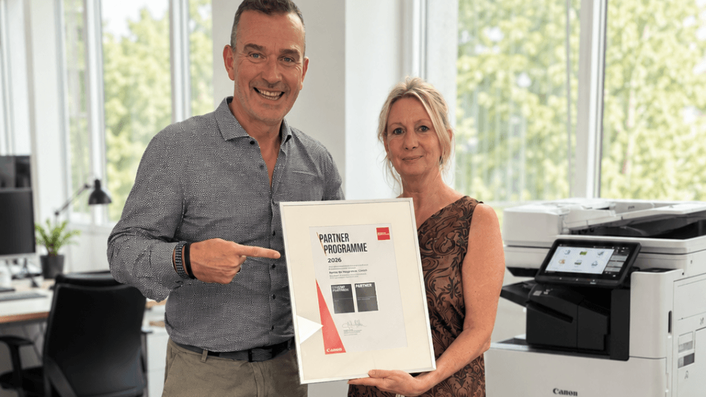 Frank Schlößer von Canon Deutschland und Carola Osbelt, Abteilungsleiterin Bürotechnik bei KNORZ, präsentieren gemeinsam die Auszeichnung „Canon Silver Partner 2026“ vor einem Canon Multifunktionssystem in einer modernen Büroumgebung.